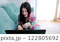 A Woman is Relaxing at Home While Using Her Laptop on a Couch Comfortably 122805692