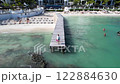 Young woman standing on wooden pier above turquoise sea near tropical beach resort 122884630