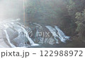 Drone Flight Over Serene Waterfall in Japanese Forest with Insects and Warm Sunlight 122988972