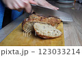 A GIRL CUTS BREAD ON A BOARD WITH A SHARP LARGE KNIFE 123033214
