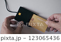 Hand swiping golden credit card through payment terminal. 123065436