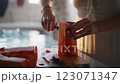 Close up of woman's hands cutting papaya fruit, pawpaw fruit in half using a knife. Female cook preparing papaya, chef in a brightly lit kitchen.  123071347