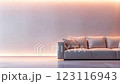 A minimalist and serene space features a plush, light-colored sofa positioned against a clean, pastel-toned wall illuminated by soft, ambient lighting, creating a tranquil and calming atmosphere. 123116943