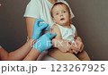A caregiver holds a baby during a vaccination appointment at a health clinic, as a healthcare professional prepares to administer the inoculation. This crucial health activity supports child health 123267925
