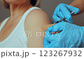 Healthcare professional administers vaccination to an individual in a clinic setting. The patient is seated calmly while receiving the inoculation in their upper arm 123267932