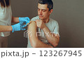 A man sits calmly as a medical professional administers a vaccination in a neutral clinic environment. The focus is on the careful procedure of inoculation 123267945