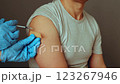 An adult is receiving a vaccination in a healthcare environment. The healthcare professional prepares to administer the shot, ensuring a safe and sterile procedure 123267946