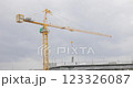 Tower cranes on the construction site, against sky is cloudy and it is about to rain. Tall yellow metal structures used for lifting and moving. workers on the rooftop of a residential building. 123326087