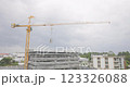 Tower cranes on the construction site, against sky is cloudy and it is about to rain. Tall yellow metal structures used for lifting and moving. workers on the rooftop of a residential building. 123326088