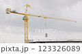Tower cranes on the construction site, against sky is cloudy and it is about to rain. Tall yellow metal structures used for lifting and moving. workers on the rooftop of a residential building. 123326089