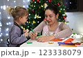 Mom shows little daughter how to decorate Christmas cookies with cream 123338079