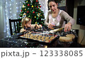 Mom takes a piece of dough to roll out while a little girl collects cut-out cookies 123338085