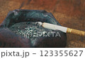 Close-up of a Smoldering Cigarette in an Ashtray on a Wooden Surface Close-up of a Smoldering Cigarette in an Ashtray on a Wooden Surface 123355627