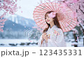 一位女子站在櫻花飄落的美麗風景中 123435331