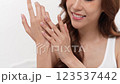 A woman of Asian descent gently applies a skincare product to her hand in a calm setting, emphasizing the importance of beauty and self-care rituals in her daily routine in a white background 123537442