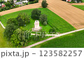 Aerial view of large field of green grass with a small building in the middle. 123582257