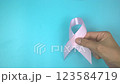Footage video 4k. Hands holding pink ribbon on blue background. Breast cancer Awareness, male breast cancer disease, World Cancer Day. Healthcare or hospital and insurance concept. 123584719