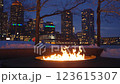 Large outdoor fire pit burning bright on a winter night at Boston Fan Pier Park with the view of the city skyscrapers in the background 123615307