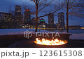 Large outdoor fire pit burning bright on a winter night at Boston Fan Pier Park with the view of the city skyscrapers in the background 123615308