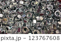 Close-up shows a pile of fasteners with threaded holes. Numerous hexagonal nuts are displayed in selective focus 123767608