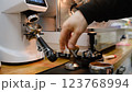 Barista tamps coffee in a portafilter with an old manual tamper inserts it into the espresso machine and prepares a drink precise process professional technique espresso brewing artistry 123768994