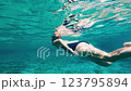 A Graceful Underwater Swimmer Glides Effortlessly Through Crystal Clear Water 123795894