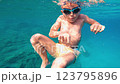 A Young Boy Swimming Enthusiastically Underwater in the Refreshing Clear Blue Water 123795896