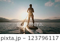 A tranquil and serene scene of a paddleboarder gliding across the calm waters during a stunning sunrise 123796117