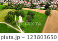 Aerial view of large field of green grass with a small building in the middle. 123803650