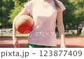 Slim young woman walking street basketball court, ball under arm, sports hobby 123877409