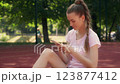 Stylish female blogger sitting on ground and using gadget to browse social media 123877412