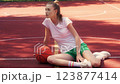 Athletic young woman sitting on basketball ground, having rest after active game 123877414