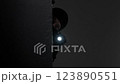 A person wearing a balaclava and holding a flashlight, partially concealed, creating a suspenseful and mysterious mood in the darkness. 123890551