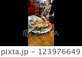 A waiter uses scissors to cut a lobster for customers at a restaurant in Nha Trang, Vietnam. Lobster baked with cheese and garlic is served with vegetables. Vertical video, real time. Selective focus. 123976649