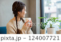 Japanese woman relaxing in a cafe, holding a paper cup of coffee by the window 124007721