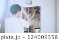 A man looking in the mirror and straightening his hair 124009358