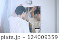 A man looking in the mirror and straightening his hair 124009359