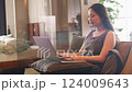 A woman who operates a laptop computer with a sofa 124009643
