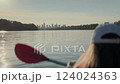 A woman paddling on a kayak on Vistula river with Warsaw cityscape in the background during sunset  124024363