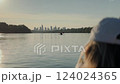 A woman paddling on a kayak on Vistula river with Warsaw cityscape in the background during sunset  124024365