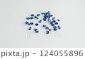 Scattered Sparkling Blue Sapphire Gemstones on White Background with Soft Elegant Light 124055896