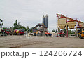 Cement plant with trucks, mixers, and silos in an industrial outdoor setting. Concrete production and construction material processing at a manufacturing facility. Industrial site photography 124206724