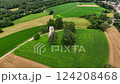 Aerial view of large field of green grass with a small building in the middle. 124208468