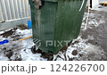 A green trash bin prominently sits in a snowy outdoor environment, fully ready for effective waste disposal 124226700