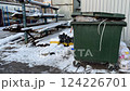 A green trash bin prominently sits in a snowy outdoor environment, fully ready for effective waste disposal 124226701
