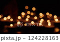Hand lighting tealight candles with a matchstick in a dark setting. Remembrance, memorial, and spiritual ritual concept for design and print 124228163