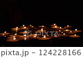 Burning tealight candles arranged on a dark surface with a hand in the background. Remembrance, memorial, and spiritual ritual concept for design and prin 124228166