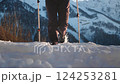Active female walker runs across snowy trail using trekking poles for stability and propulsion 124253281