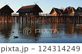 Beautiful lakeside huts at sunset with ducks swimming in calm waters 124314249