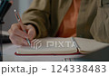 Woman taking notes in a cozy home office while working remotely 124338483
